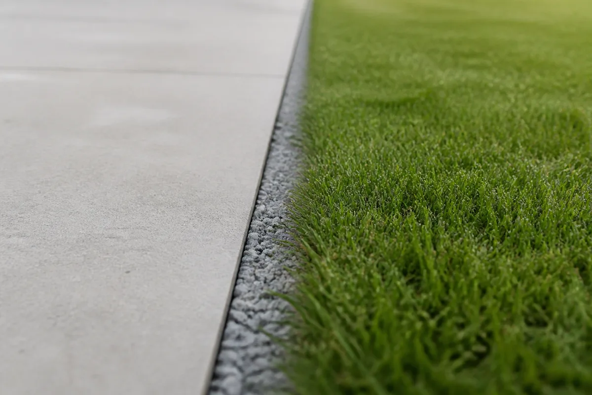 Terrasse en béton clair posée de plain-pied au niveau d&rsquo;une pelouse, sans ressaut ni garde-corps